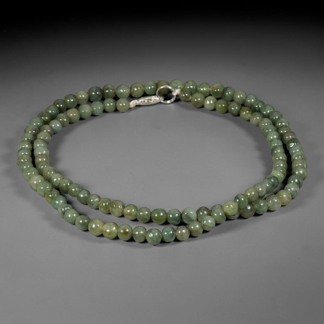 Natural Burmese Type A Green Mottled Jadeite Jade Beaded Necklace, 15TF: Smooth round natural Burmese Type A jadeite beads measuring 5.7mm, displaying blended muted forest green tones with subtle natural colour variations across the strand. Finished with a sterling silver 