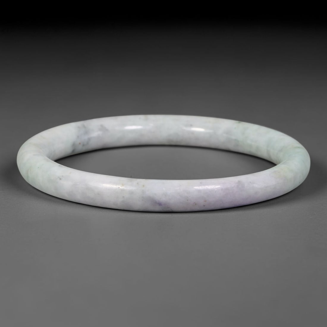 Natural Burmese Type A Pale Lavender Speckled Floating Green Jadeite Jade Bangle Bracelet, 64TD: Polished from natural Burmese jadeite, this slender round bangle has a milky pale white base softened by faint pale lavender tones and subtle wisps of floating green alongside minor dark mineral speck