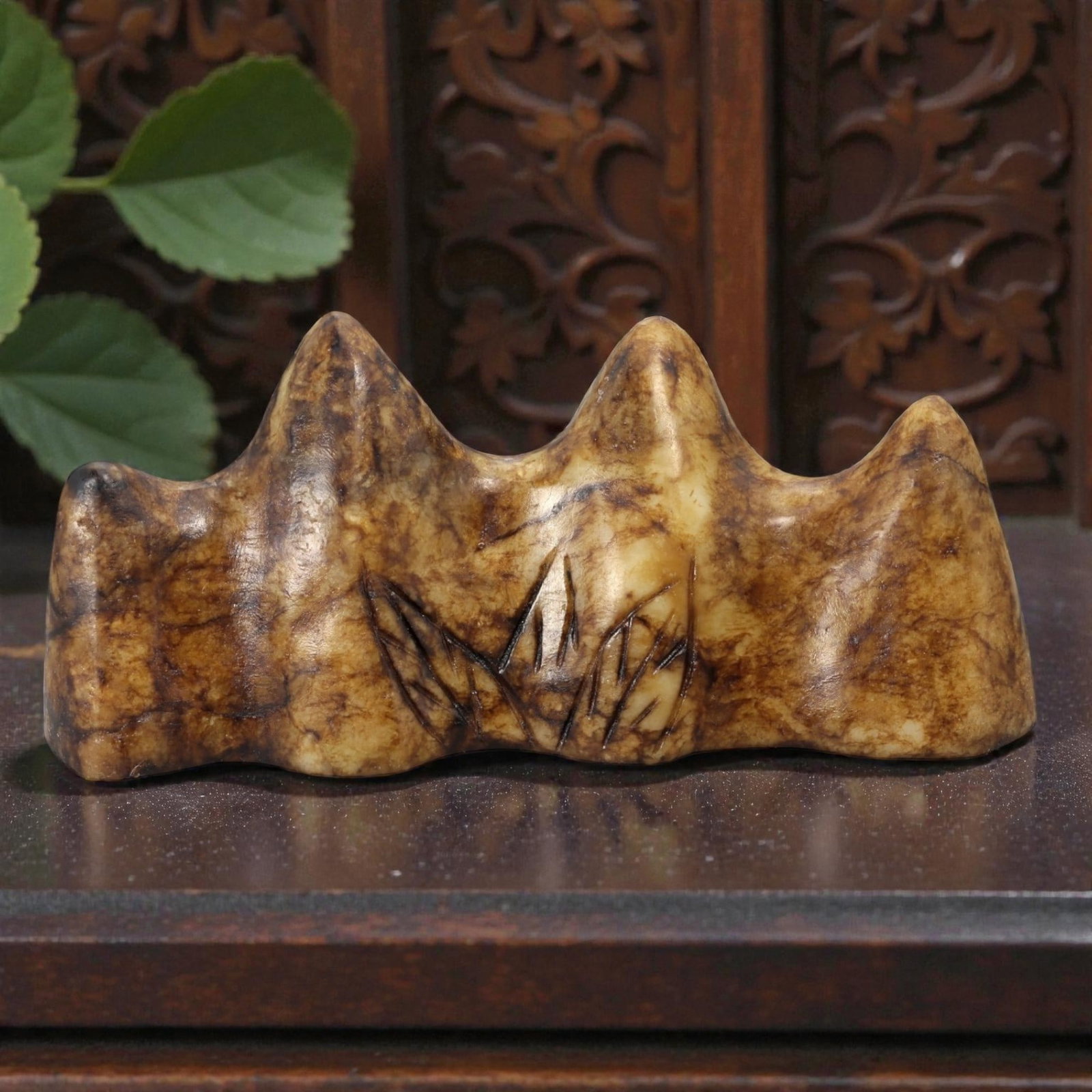A Chinese Hardstone Brush Rest, 20th Century, 10YB: Carved from mottled brown and buff-toned hardstone with natural veining and tonal variation, the object is worked as a horizontal brush rest with an undulating upper profile formed by a series of roun