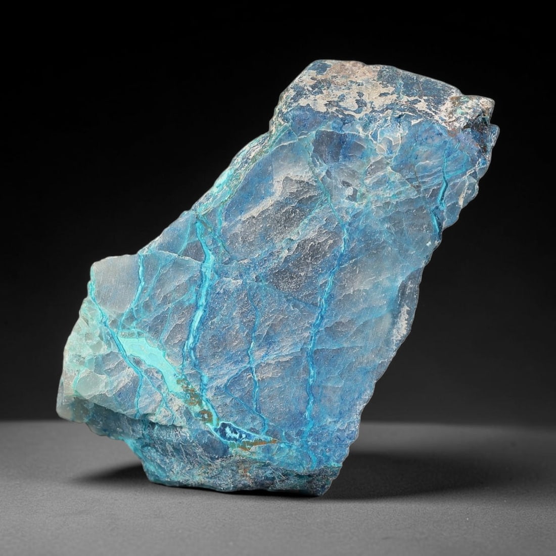 64ct Natural Peruvian Chrysocolla Polished Slab Rough, 70WV: This partial-polished chrysocolla slab features blended mineral matrix with smooth refined face and unaltered natural rugged edge across its 41x21x8mm elongated form, translucent mineral layers hold s