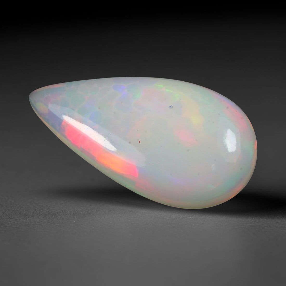 7.76ct Natural Ethiopian Welo Solid Opal Pear Cabochon Loose Gemstone, 20TG: Solid opal cabochon mined from Ethiopia's Welo opal deposits, fashioned into an elongated slender pear teardrop dome with a smooth high-gloss polish. The translucent milky host matrix showcases promin
