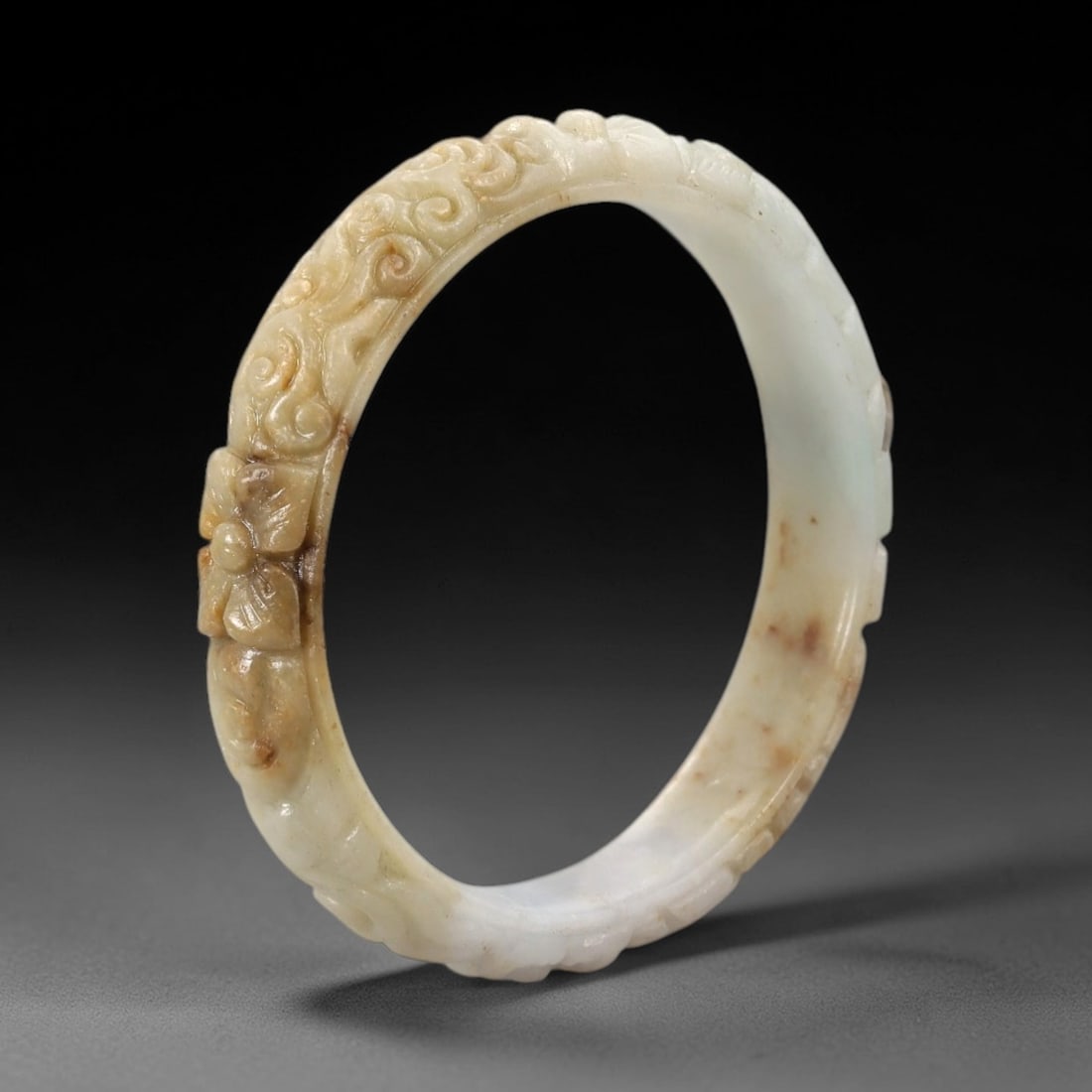Natural Burmese Type A Carved Jadeite Jade Bangle Bracelet, 59ZL: A fine jadeite bangle of flattened circular form, masterfully carved in relief with a continuous band of scrolling foliate and floral motifs. The stone exhibits a striking variegated palette, with a t