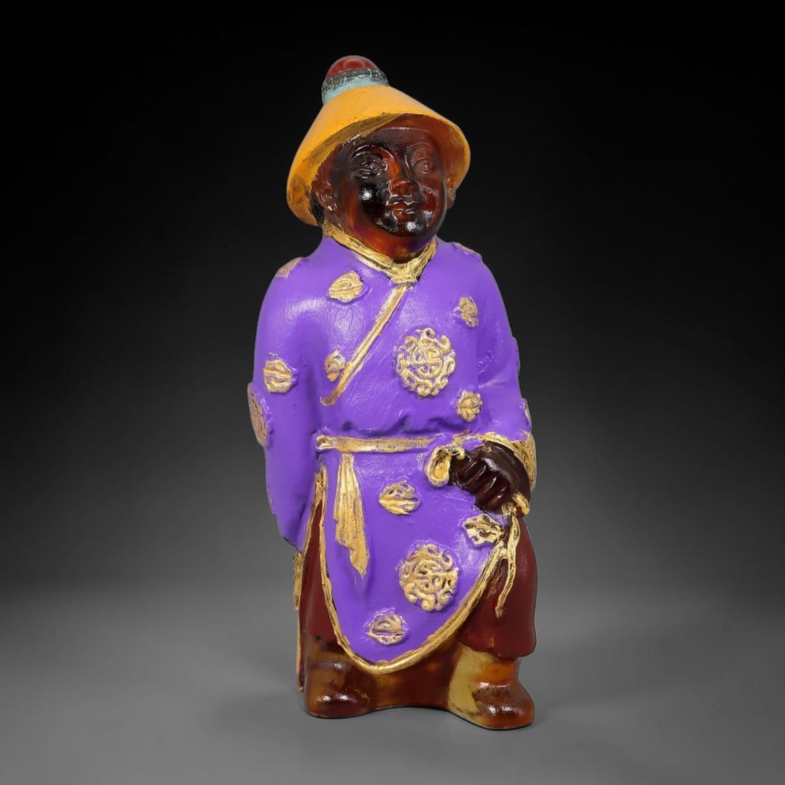 Vintage Chinese Liuli Glass Snuff Bottle - Standing Robed Attendant, 85YF: This snuff bottle is moulded from translucent amber liuli glass, formed as a standing attendant wearing a traditional brimmed hat topped with a red bead stopper. The vibrant purple robe is adorned wit