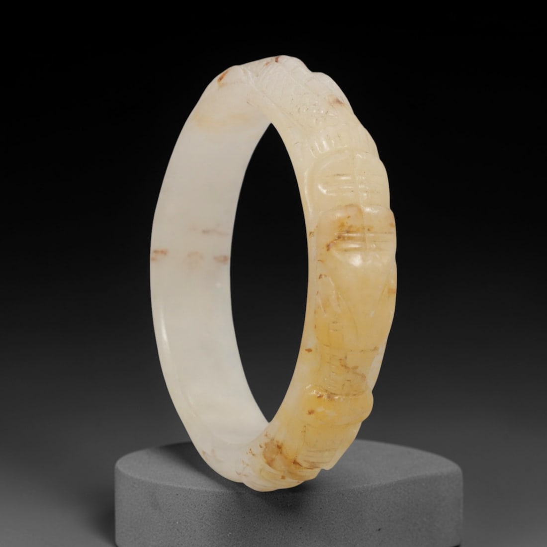 Natural Burmese Type A Carved Jadeite Jade Bangle Bracelet, 46ZL: A fine jadeite bangle of circular form, masterfully carved in relief with a continuous band of a sinuous dragon coiling around its circumference. The stone exhibits a translucent creamy white base, wi