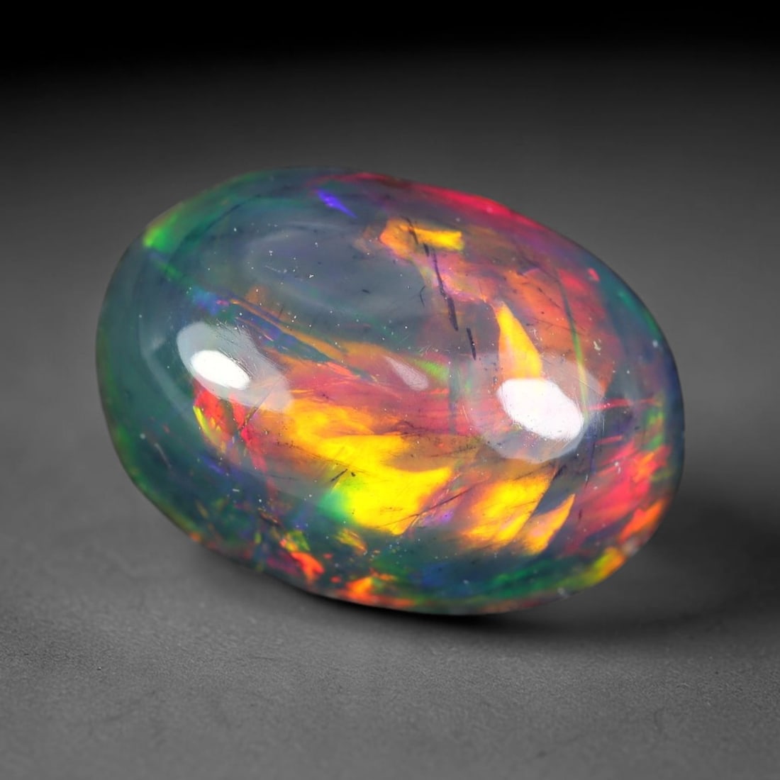 2.33ct Natural Ethiopian Welo Black Smoked Opal Cabochon Loose Gemstone, 86WP: This fully polished Ethiopian Welo opal features a dark smoked base with vivid, sweeping play-of-color shifting across its glossy dome surface, measured at 10.6x7.4x5.5mm. The black smoke treatment de