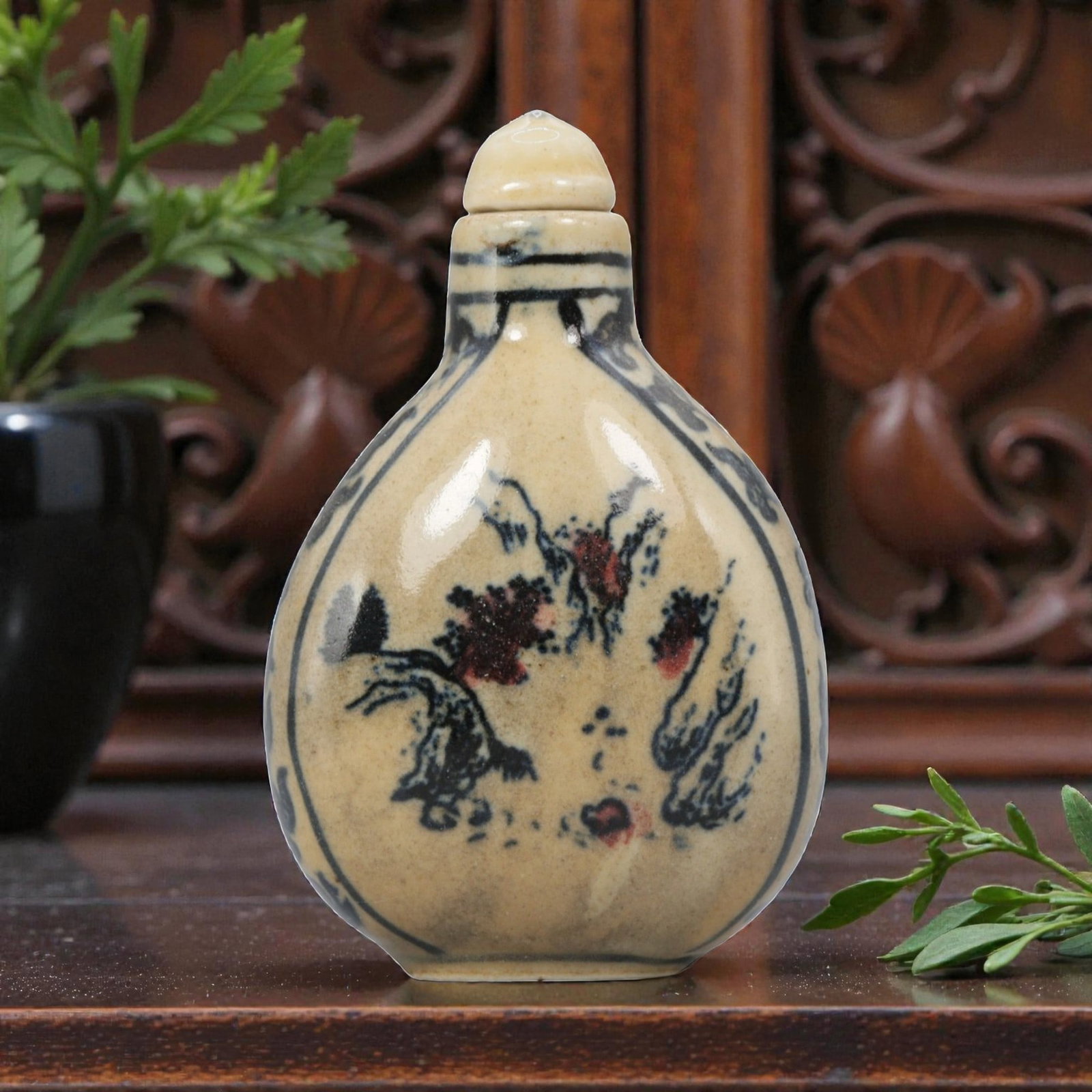 A Chinese Porcelain Snuff Bottle, 20th Century, 3YD: Crafted from porcelain with a pale cream glaze and decorated in underglaze blue with copper red accents, the snuff bottle features a flattened, pear-shaped body, a short cylindrical neck, and a domed 