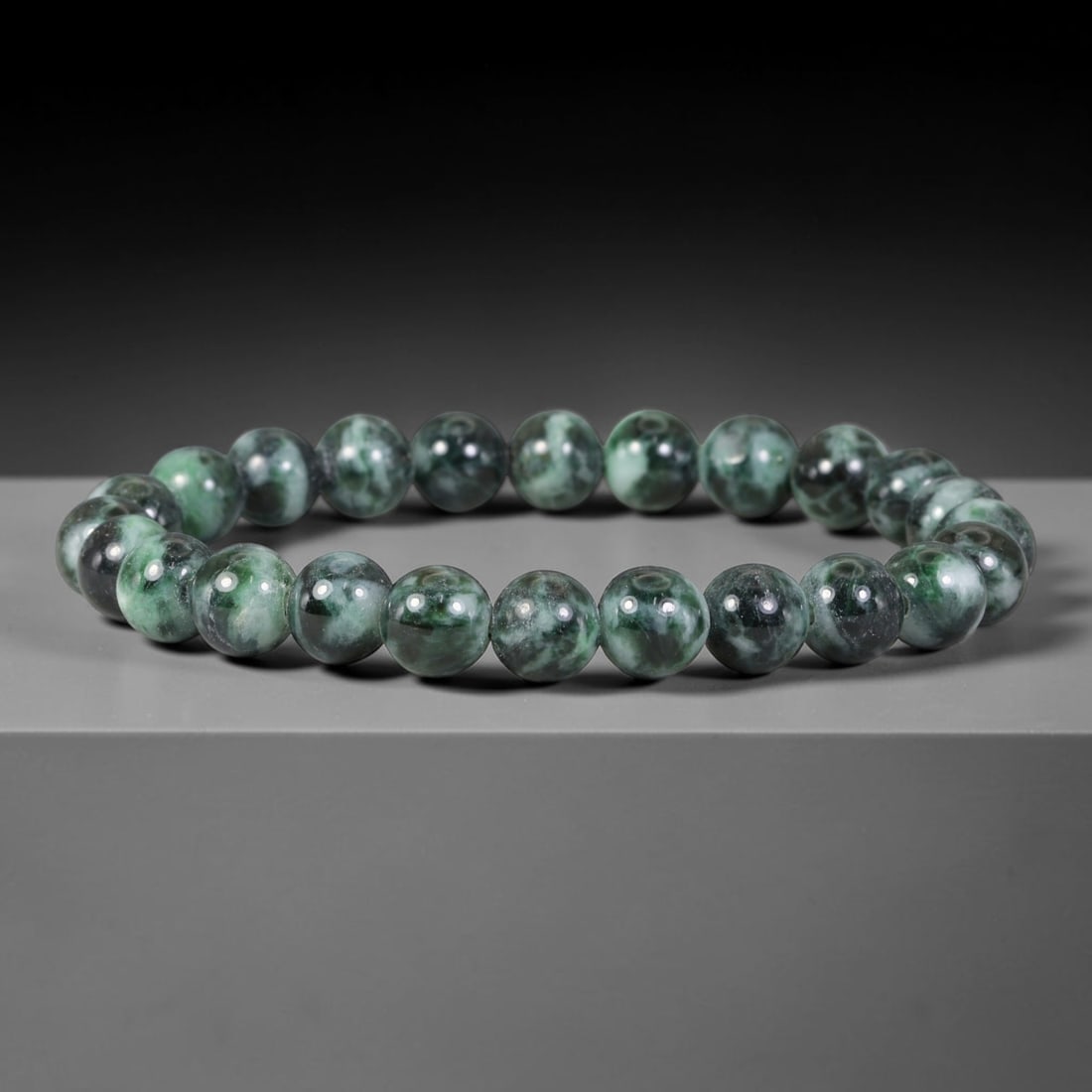 Natural Burmese Type A Dark Emerald Cloud Mottled Jadeite Jade Bead Bracelet, 38TP: Strung from natural Type A Burmese jadeite, this spherical bead bracelet features deep emerald green blended with pale celadon cloud-like mottled patches across each bead. Every bead is smoothly polis