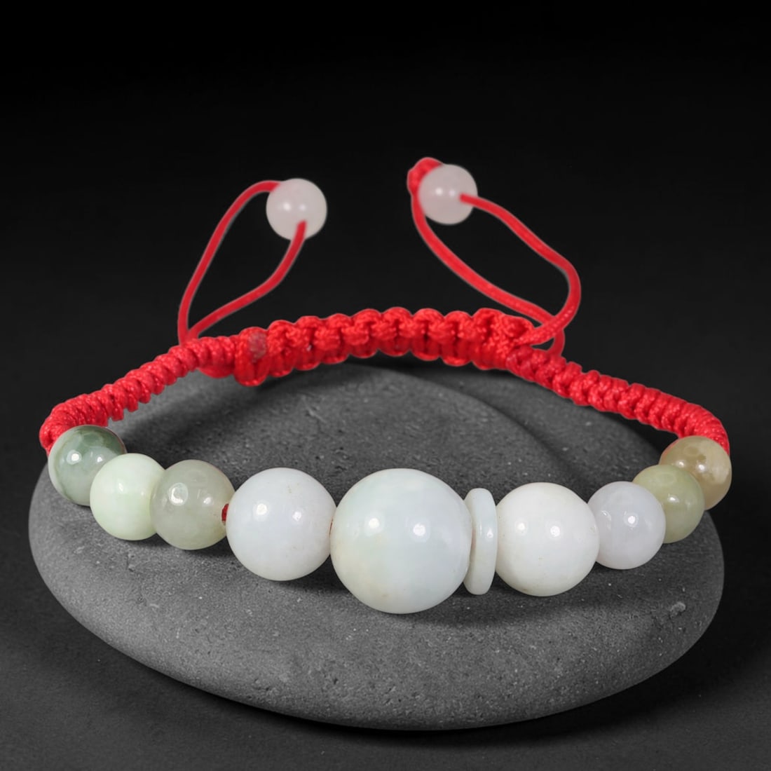 Natural Burmese Type A Pale Celadon Graduated Jadeite Adjustable Red Braided Cord Bracelet, 19TP: Handcrafted adjustable red braided cord bracelet, set with natural Type A Burmese jadeite graduated round beads in blended pale celadon and milky white tones. A prominent central focal bead paired wit
