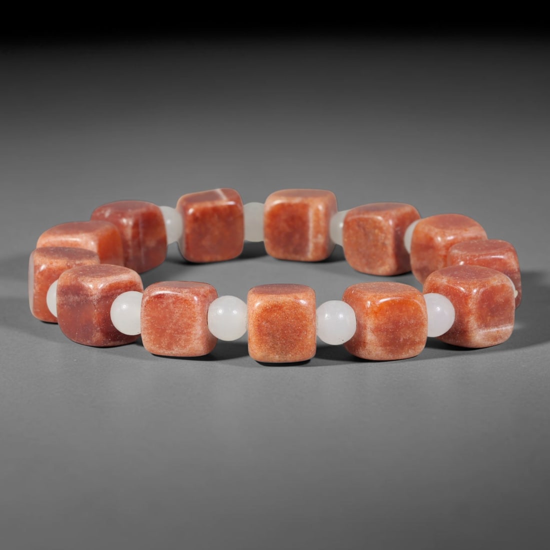 Natural Red Sunstone Cube Beaded Bracelet with White Jadeite Spacers, 51TP: Polished elastic strand bracelet hand-strung with natural warm terracotta-red sunstone cube beads, separated by smooth round white jadeite spacer beads. Natural subtle colour banding and fine sparklin