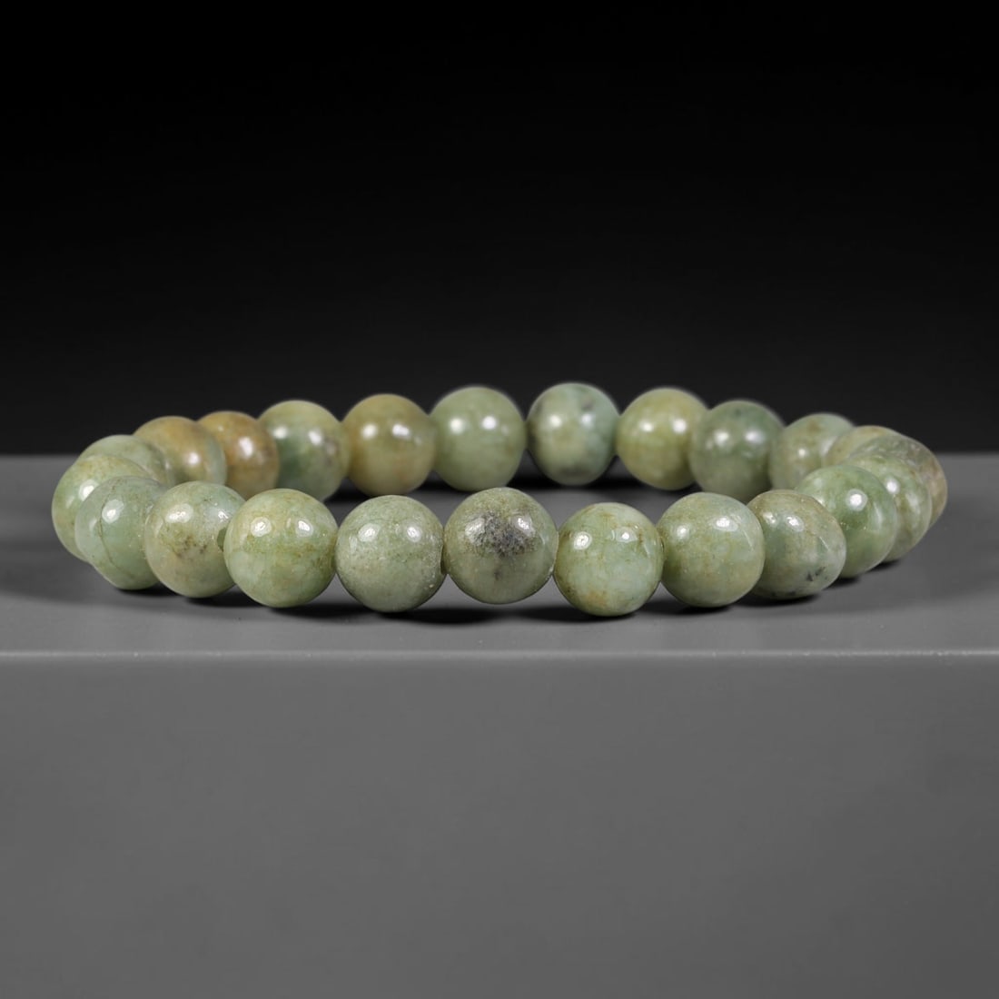 Natural Burmese Type A Mottled Pale Sage Green Jadeite Jade Bead Bracelet, 97TK: Strung from natural Type A Burmese jadeite, this spherical bead bracelet carries a muted pale sage green base marked by scattered dark mineral speckling and faint warm ochre undertones across the bead