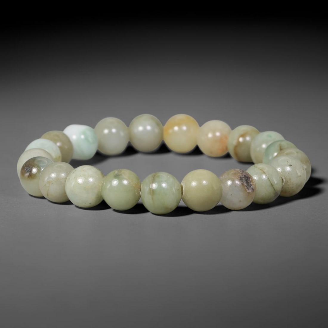 Natural Burmese Type A Mottled Celadon Jadeite Jade Round Bead Bracelet, 94TK: Polished from natural Burmese Type A jadeite, this bracelet features smooth round mottled celadon beads measuring 9.6mm. It carries soft celadon, pale cream and warm yellow tones with distinct dark na