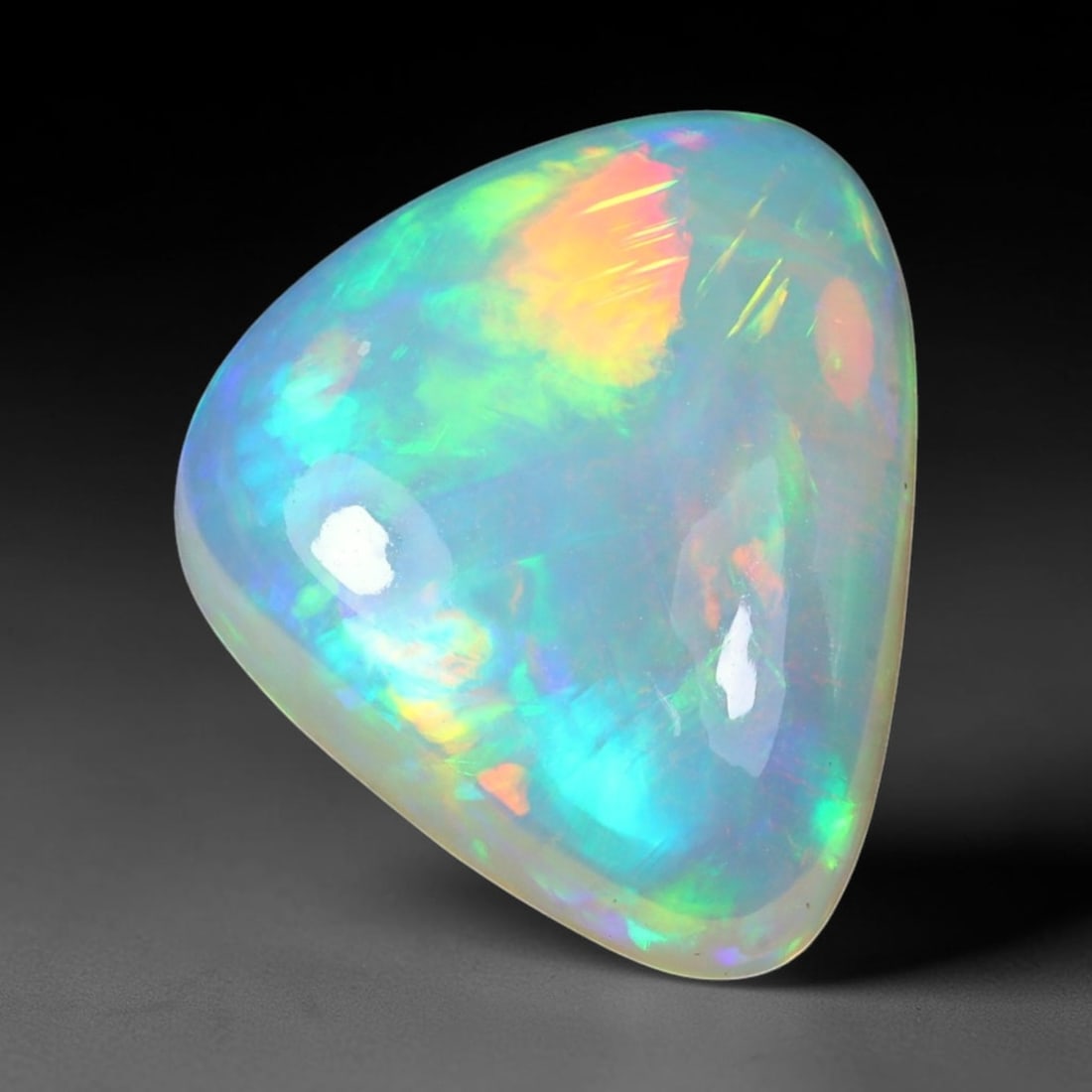 7.75ct Natural Ethiopian Welo Solid Opal Trillion Cabochon Loose Gemstone, 5TG: Solid opal cabochon sourced from Ethiopia's Welo mining region, shaped to a smooth rounded trillion cabochon cut with a high-gloss polished dome. The translucent pale milky base displays vivid banded 