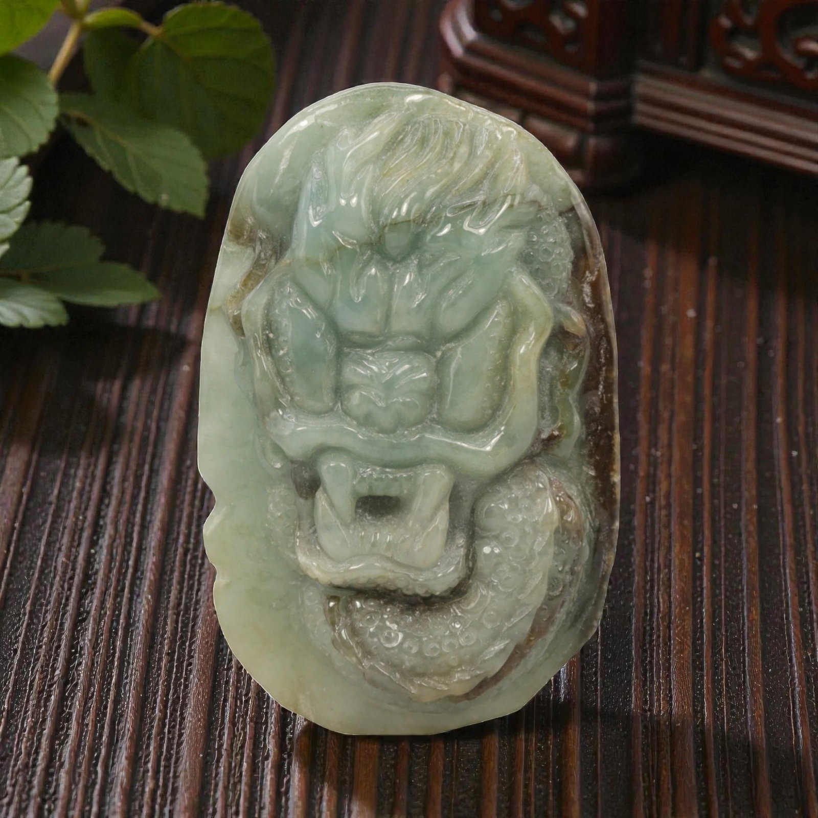 Natural Burmese Type A Jadeite Jade Dragon Pendant, 20th Century, 8ZL: Carved from pale green jadeite with natural brownish inclusions along the edges, the object is formed as an irregularly oval pendant. The front is decorated in high relief with a dragon head, featurin