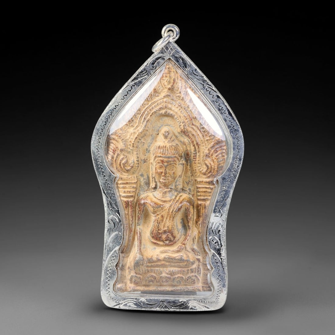 Thai Gilded Clay Buddha Amulet - Silver Cased Votive Pendant, 1YY: Formed from clay finished with subtle gilded metal detailing, this devotional piece features seated Buddha iconography framed within intricately molded temple arch motifs. The relief carving displays 