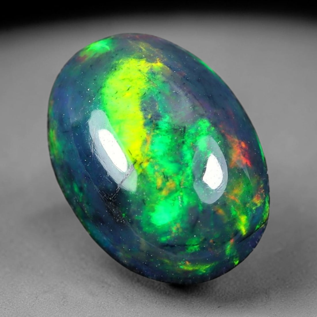 1.96ct Natural Ethiopian Welo Black Smoked Opal Cabochon Loose Gemstone, 83TG: This fully polished Ethiopian Welo opal features a dark smoked base with vivid, sweeping play-of-color shifting across its glossy dome surface, measured at 10.8x7.9x4.7mm. The black smoke treatment de