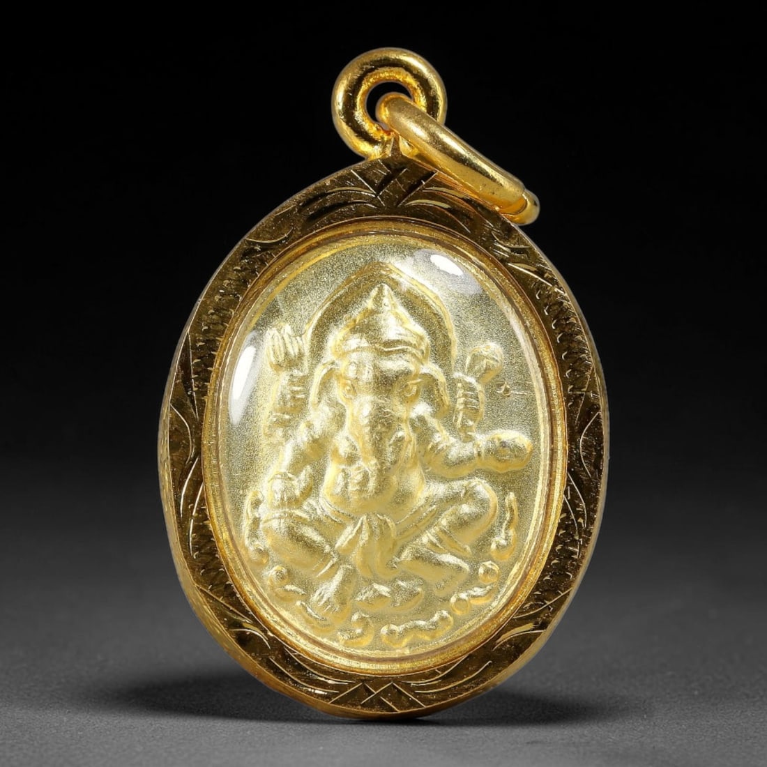 Thai Oval Ganesha Dual-Sided Gold Plated Metal Casing Amulet, 52YY: Oval-shaped Thai Ganesha elephant god amulet enclosed in finely engraved golden frame with transparent protective cover. The front side features detailed embossed four-armed seated Ganesha relief, the