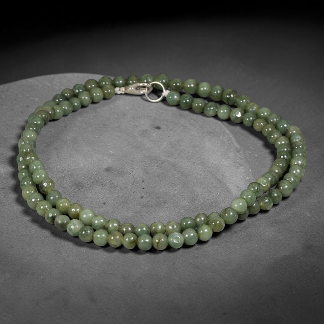 Natural Burmese Type A Green Mottled Jadeite Jade Beaded Necklace, 17TF: Smooth round natural Burmese Type A jadeite beads measuring 5.7mm, displaying blended muted forest green tones with subtle natural colour variations across the strand. Finished with a sterling silver 