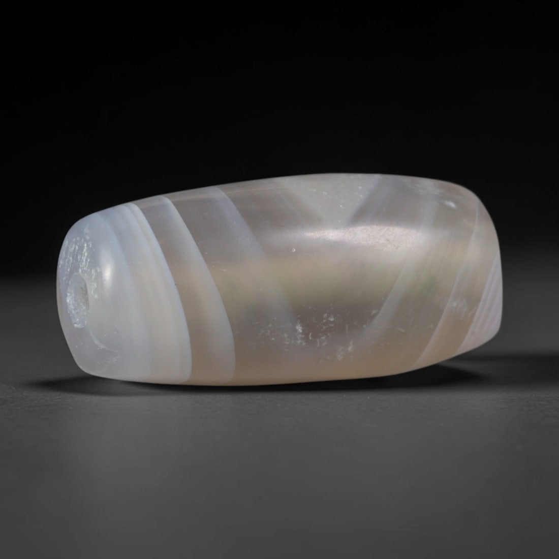 Ancient Kushan Empire Banded Agate Cylinder Bead (30 CE-375 CE), 57XD: This antique slender cylindrical banded agate bead originates from the Kushan Empire, a vital cross-continental Silk Road civilization merging Central Asian and South Asian craft techniques to manufac