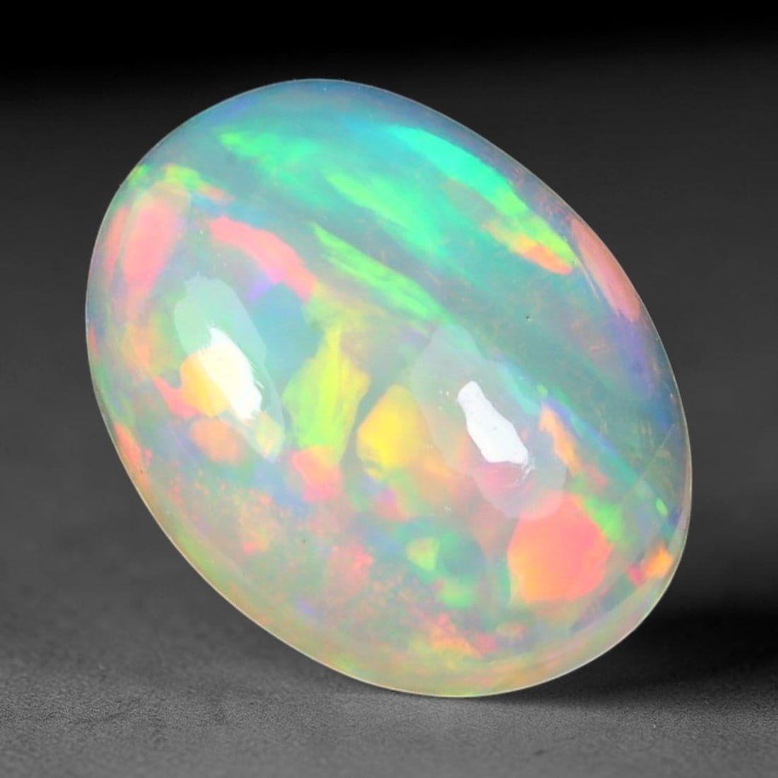 2.10ct Natural Ethiopian Welo Solid Opal Oval Cabochon Loose Gemstone, 66TG: Solid opal cabochon mined from Ethiopia's Welo opal deposits, polished into a smooth elongated oval dome with high reflective gloss. The translucent pale milky base hosts broad shifting play-of-color 