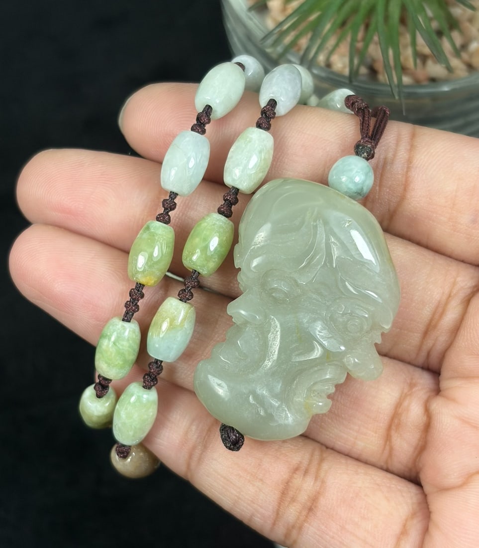 Burmese Jadeite Beaded Necklace with Hetian Jade Luohan Head Pendant, 93YJ: This necklace features a hand-carved Hetian jade luohan head pendant paired with natural Burmese jadeite pebble beads, strung on a brown cord. The pendant is crafted from pale Hetian jade with subtle 