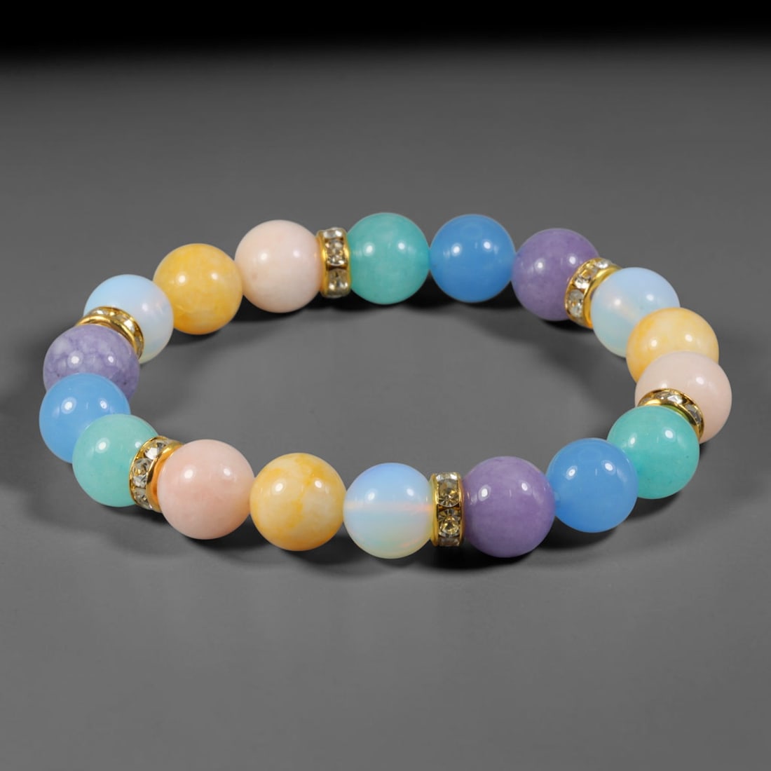 Natural Mixed Stone Beaded Bracelet - Polished Round Bead Strand, 41YM: This elastic stretch bracelet is composed of uniformly spherical polished natural mineral beads separated by gold-toned metal spacers with clear crystalline inlays. The stone material features soft pa