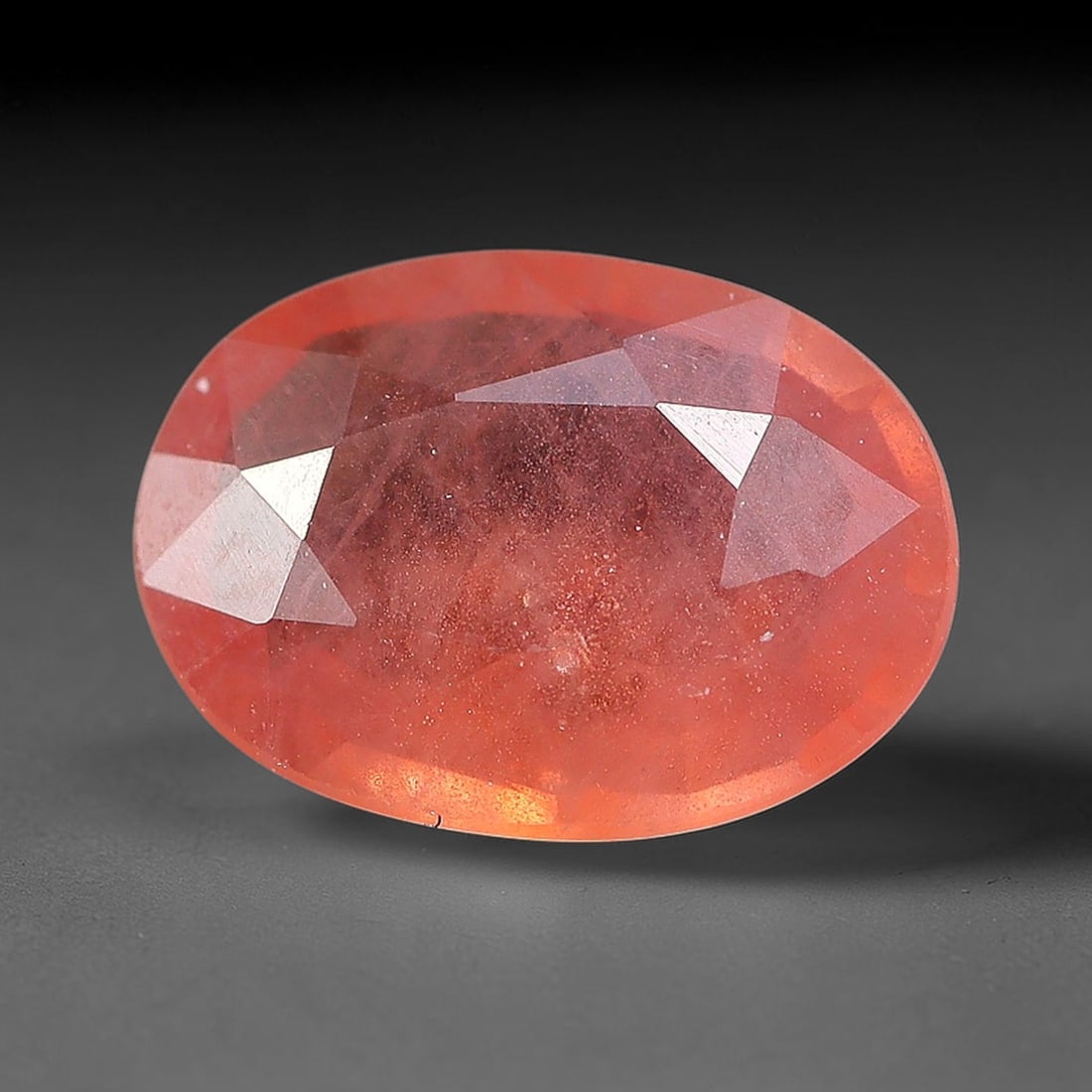 0.75ct Natural Orange Red Sapphire Oval Faceted Loose Gemstone, 74YW: This faceted gemstone consists of natural sapphire, cut in a oval shape with polished facets that showcase its orange red colouration. Natural internal inclusions and surface characteristics are visib