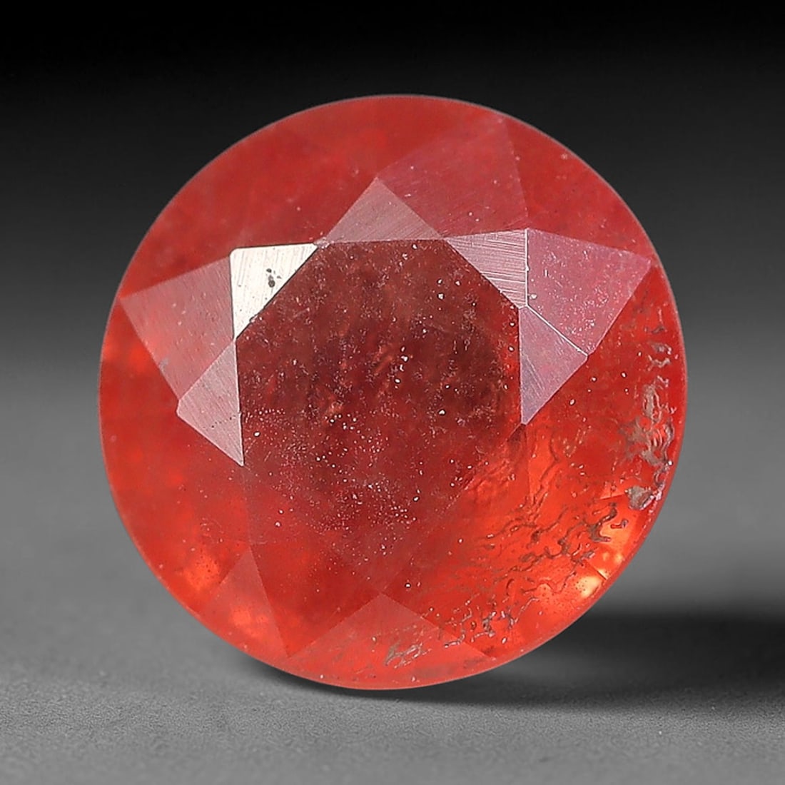 1.12ct Natural Orange Red Sapphire Round Faceted Loose Gemstone, 86YW: This faceted gemstone consists of natural sapphire, cut in a round shape with polished facets that showcase its orange red colouration. Natural internal inclusions and surface characteristics are visi