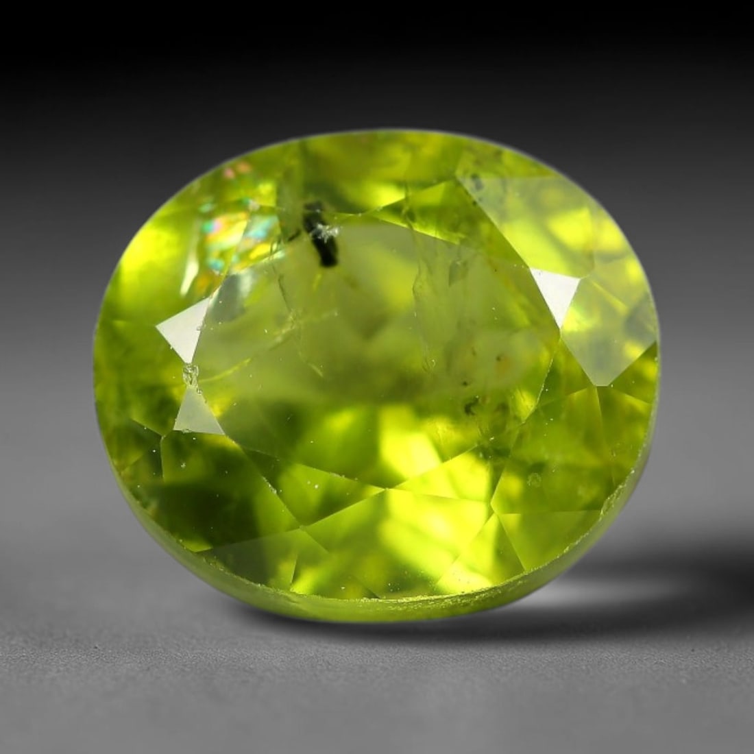 5.94ct Natural Pakistan Green Peridot Oval Faceted Gemstone, 24YW: This faceted gemstone consists of natural Pakistani peridot, fashioned into an oval cut with polished facets that highlight its vivid green body colour. Natural mineral inclusions are visible within t