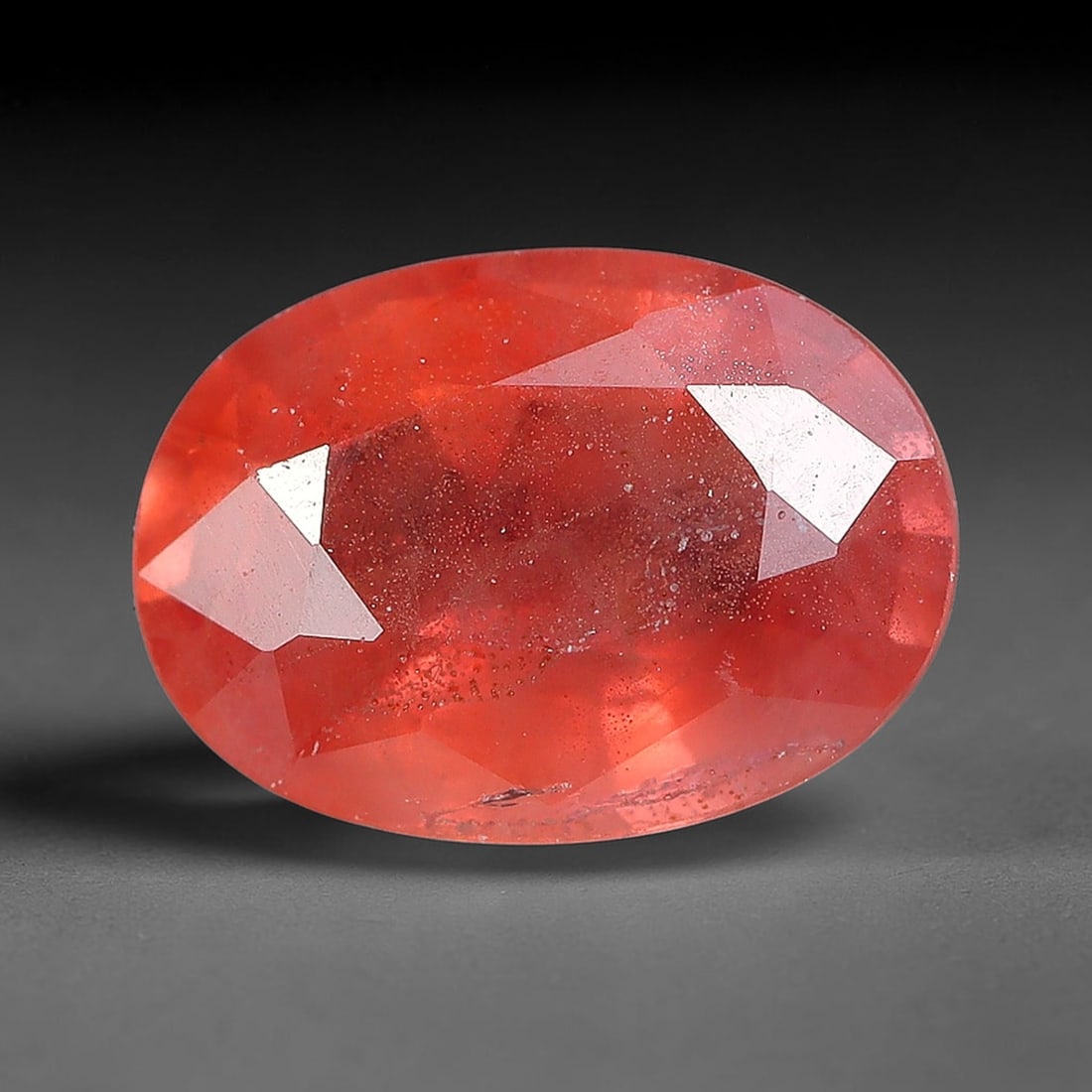 1.00ct Natural Orange Red Sapphire Oval Faceted Loose Gemstone, 79YW: This faceted gemstone consists of natural sapphire, cut in a oval shape with polished facets that showcase its orange red colouration. Natural internal inclusions and surface characteristics are visib