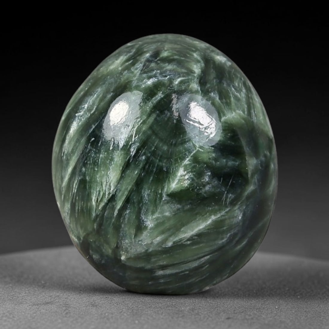 3.67 Carats Natural Deep Green Siberian Seraphinite Polished Cabochon, 94WW: This is a fully natural polished seraphinite specimen sourced from Siberian deposits, displaying distinct feathery fibrous inclusions that create beautiful flowing chatoyant patterns across its smooth