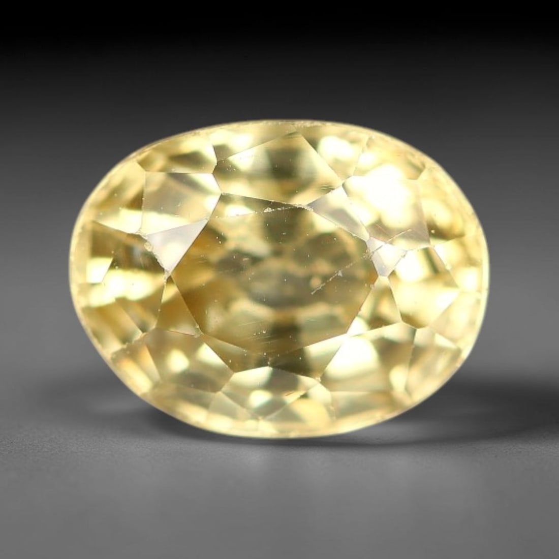 1.94ct Natural Pale Golden Yellow Zircon Oval Cut Loose Gemstone, 17TM: This faceted specimen is natural zircon, fashioned in an oval brilliant cut. The stone displays a translucent pale golden yellow hue, with visible internal inclusions and fine surface traces consisten