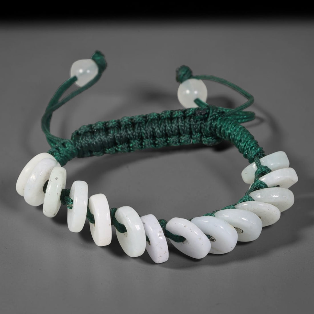 Natural Burmese Type A Milky White Donut Jadeite Adjustable Braided Cord Bracelet, 23TP: Handcrafted adjustable dark green braided cord bracelet, set with natural Type A Burmese jadeite donut beads in soft milky white tone. These flat disc beads feature subtle natural mineral speckling an