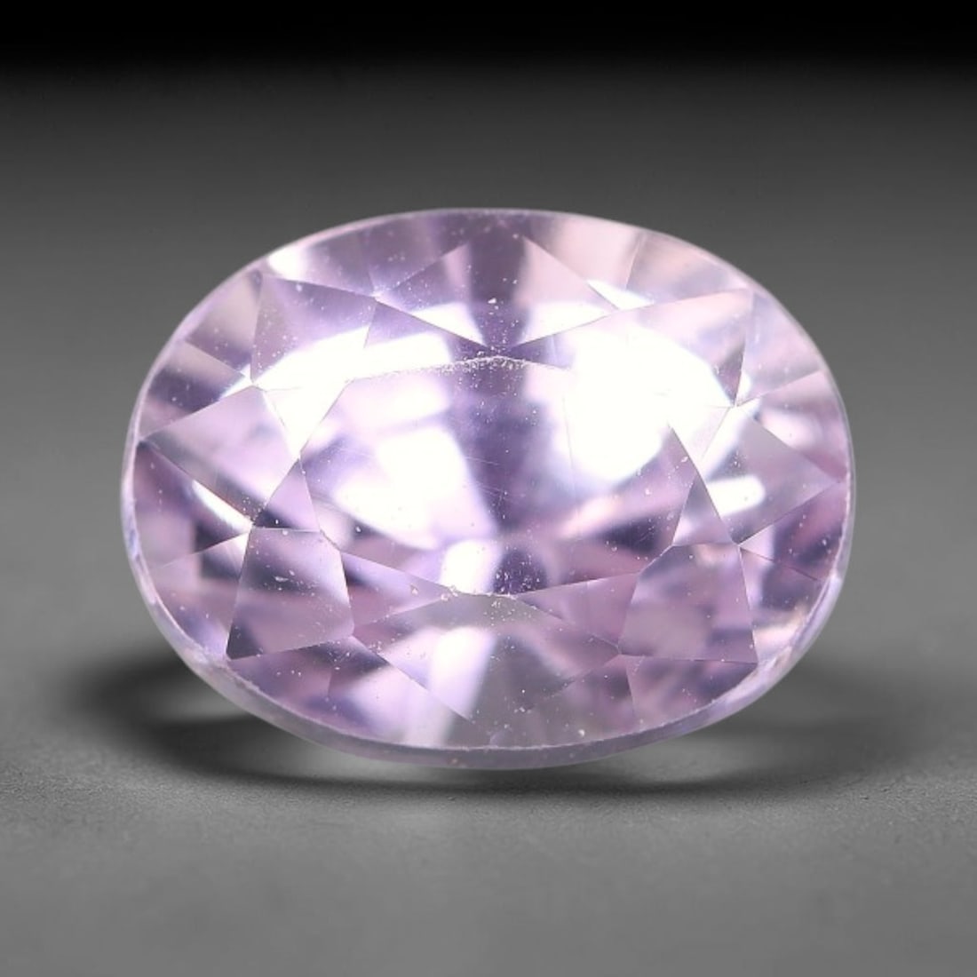 3.93ct Natural Pale Lavender Kunzite Oval Cut Loose Gemstone, 68TH: This faceted specimen is natural kunzite, fashioned in an oval brilliant cut. The stone holds a translucent pale lavender hue, with fine scattered particulate inclusions visible within the crystal mat