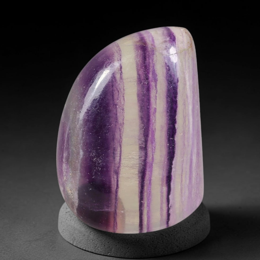 120ct Natural Banded Fluorite Freeform Polished Specimen, 43TH: This polished specimen is natural banded fluorite, shaped into a smooth freeform teardrop silhouette. Distinct vertical banding features deep violet, soft lavender and creamy off-white layers througho