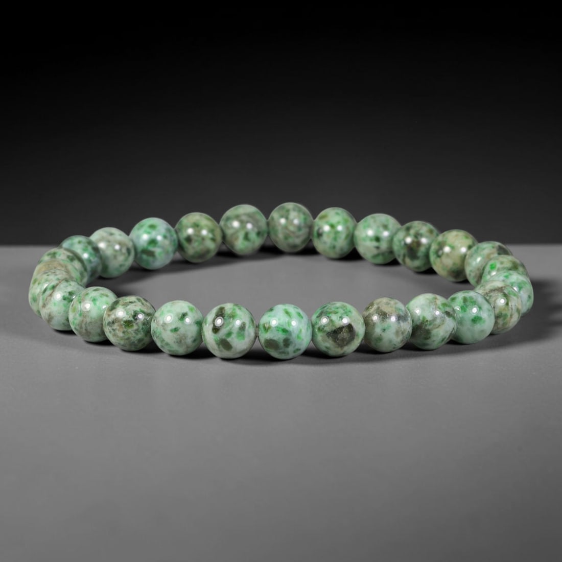 Natural Burmese Type A Spotted Emerald Moss Jadeite Jade Bead Bracelet, 39TP: Strung from natural Type A Burmese jadeite, this spherical bead bracelet features a pale base heavily marked with rich spotted emerald and moss green mottling across each bead. Every bead is smoothly 