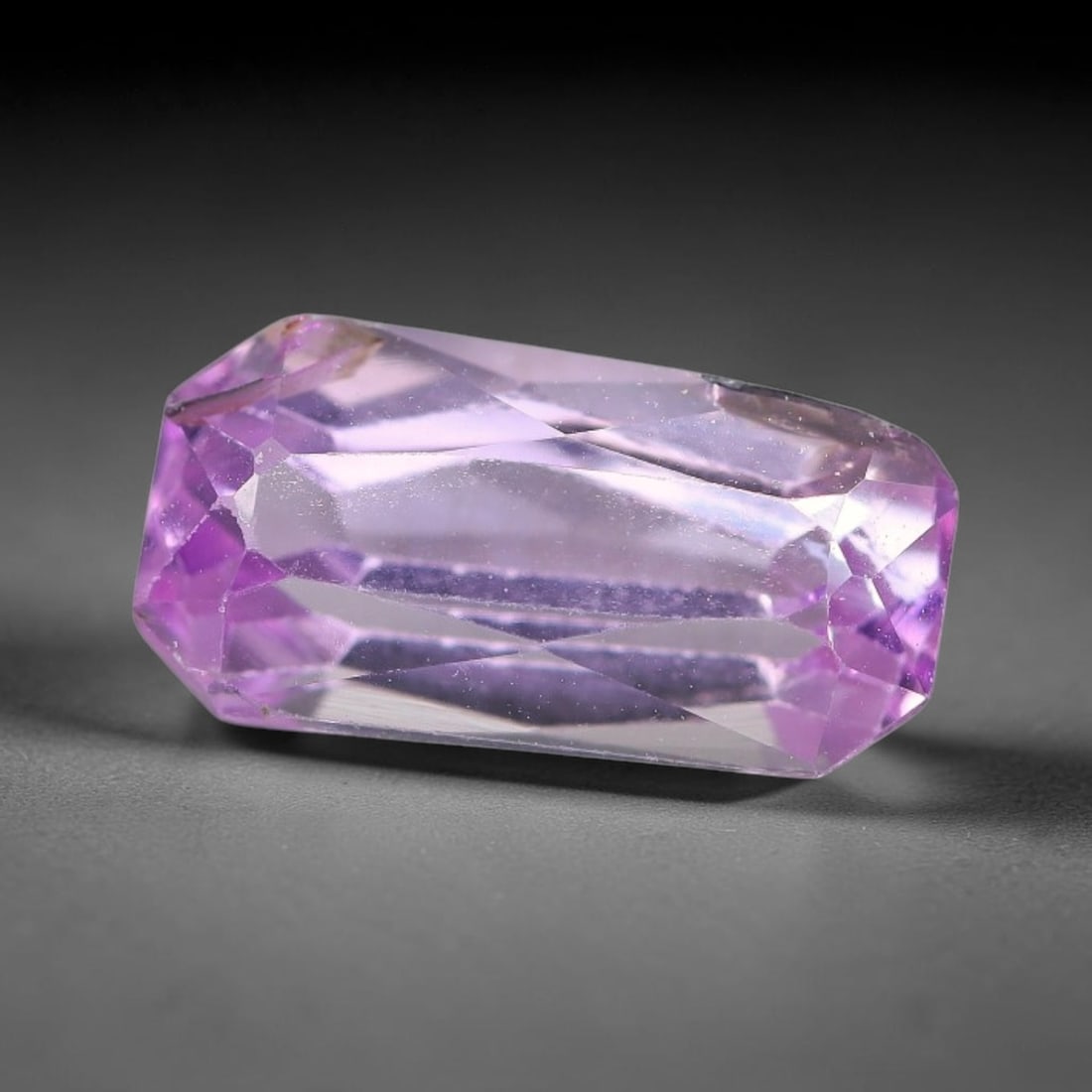 2.84ct Natural Pinkish Lavender Kunzite Emerald Cut Loose Gemstone, 65TH: This faceted specimen is natural kunzite, fashioned in an emerald cut. The stone exhibits a translucent pinkish lavender hue, with fine scattered particulate inclusions visible within the crystal matr