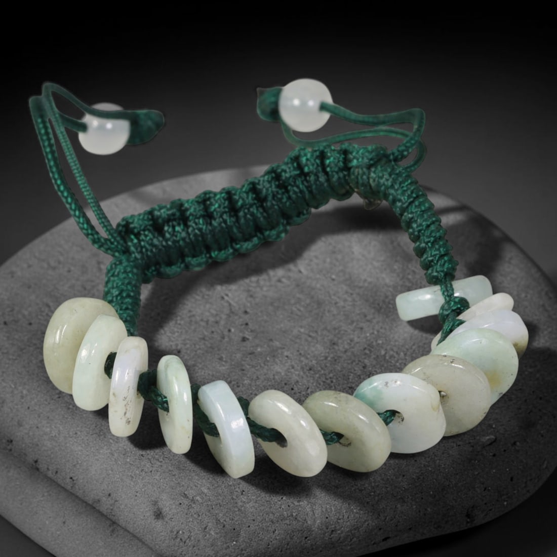 Natural Burmese Type A Pale Celadon Donut Jadeite Adjustable Braided Cord Bracelet, 16TP: Handcrafted adjustable deep green braided cord bracelet, strung with natural Type A Burmese jadeite donut beads in soft pale celadon tones. These flat disc beads show gentle natural colour gradients a