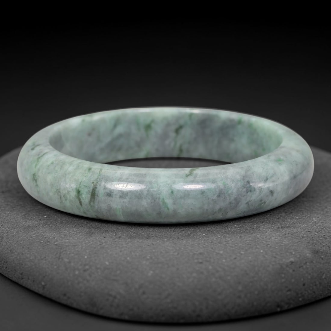 Natural Burmese Type A Jadeite Jade Bangle Bracelet, 25TD: Crafted from natural Burmese type-A jadeite, this thick compact-size bangle displays a muted cool greyish-celadon base with fine wispy green thread-like inclusions dispersed evenly across the band. It
