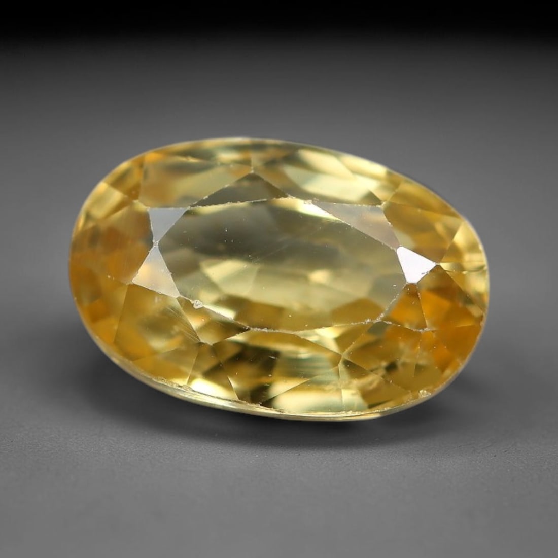 2.35ct Natural Pale Golden Yellow Zircon Oval Cut Loose Gemstone, 14TM: This faceted specimen is natural zircon, fashioned in an oval brilliant cut. The stone displays a translucent pale golden yellow hue, with visible internal inclusions and fine surface traces consisten