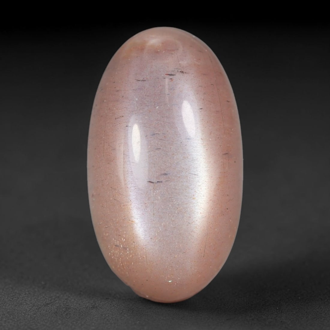 13.52 Carats Natural Ceylon Peach Fibrous Inclusion Moonstone Oval Cabochon Loose Gemstone, 87WS: This warm peach-toned Ceylon moonstone oval cabochon features a translucent soft blush feldspar base densely streaked with fine dark fibrous mineral inclusions that span the length of the elongated st