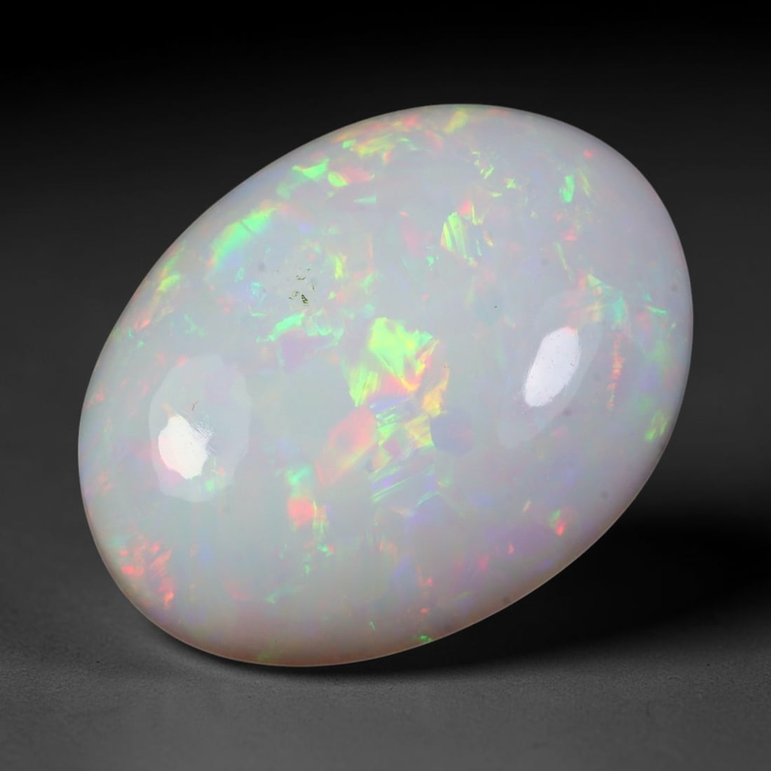 16.56ct Natural Ethiopian Welo Solid Opal Oval Cabochon, 12TG: This natural solid opal cabochon originates from Ethiopia Welo. The milky base displays vibrant multi-color play-of-color featuring bright green, red, yellow and iridescent flashes across the polished