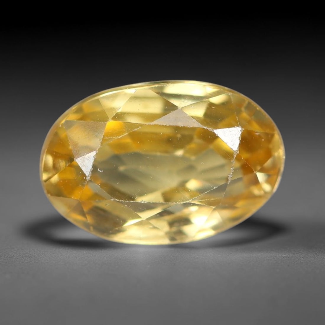 2.94ct Natural Pale Golden Yellow Zircon Oval Cut Loose Gemstone, 20TM: This faceted specimen is natural zircon, fashioned in an oval brilliant cut. The stone displays a translucent pale golden yellow hue, with visible internal inclusions and fine surface traces consisten