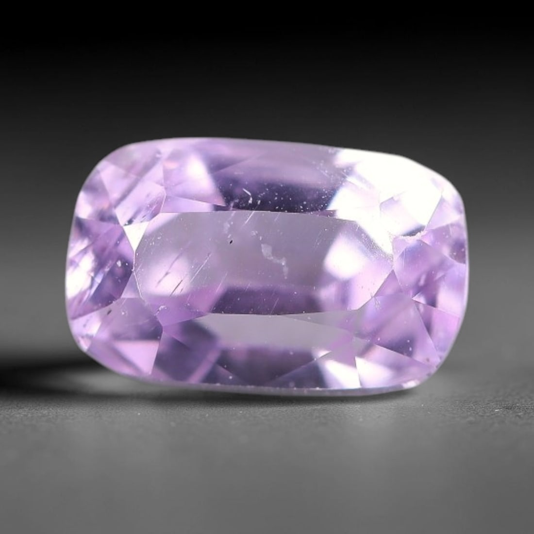 2.72ct Natural Soft Lavender Kunzite Cushion Cut Loose Gemstone, 64TH: This faceted specimen is natural kunzite, fashioned in a cushion cut. The stone displays a translucent soft lavender hue, with fine needle-like inclusions and minute particulates visible within the cr