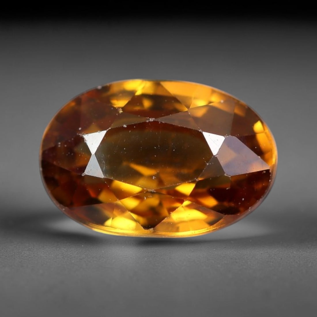 2.69ct Natural Golden Brown Zircon Oval Cut Loose Gemstone, 22TM: This faceted specimen is natural zircon, fashioned in an oval brilliant cut. The stone exhibits a translucent golden brown hue, with fine particulate inclusions visible within the crystal matrix. Face