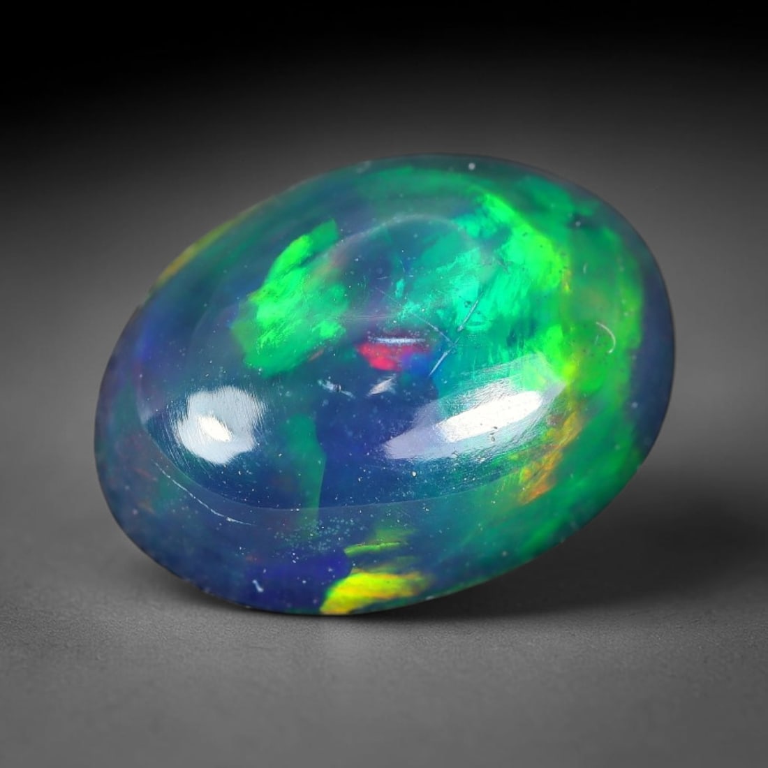 1.49ct Natural Ethiopian Welo Black Smoked Opal Cabochon Loose Gemstone, 94WP: This fully polished Ethiopian Welo opal features a dark smoked base with vivid, sweeping play-of-color shifting across its glossy dome surface, measured at 10.0x7.5x4.3mm. The black smoke treatment de