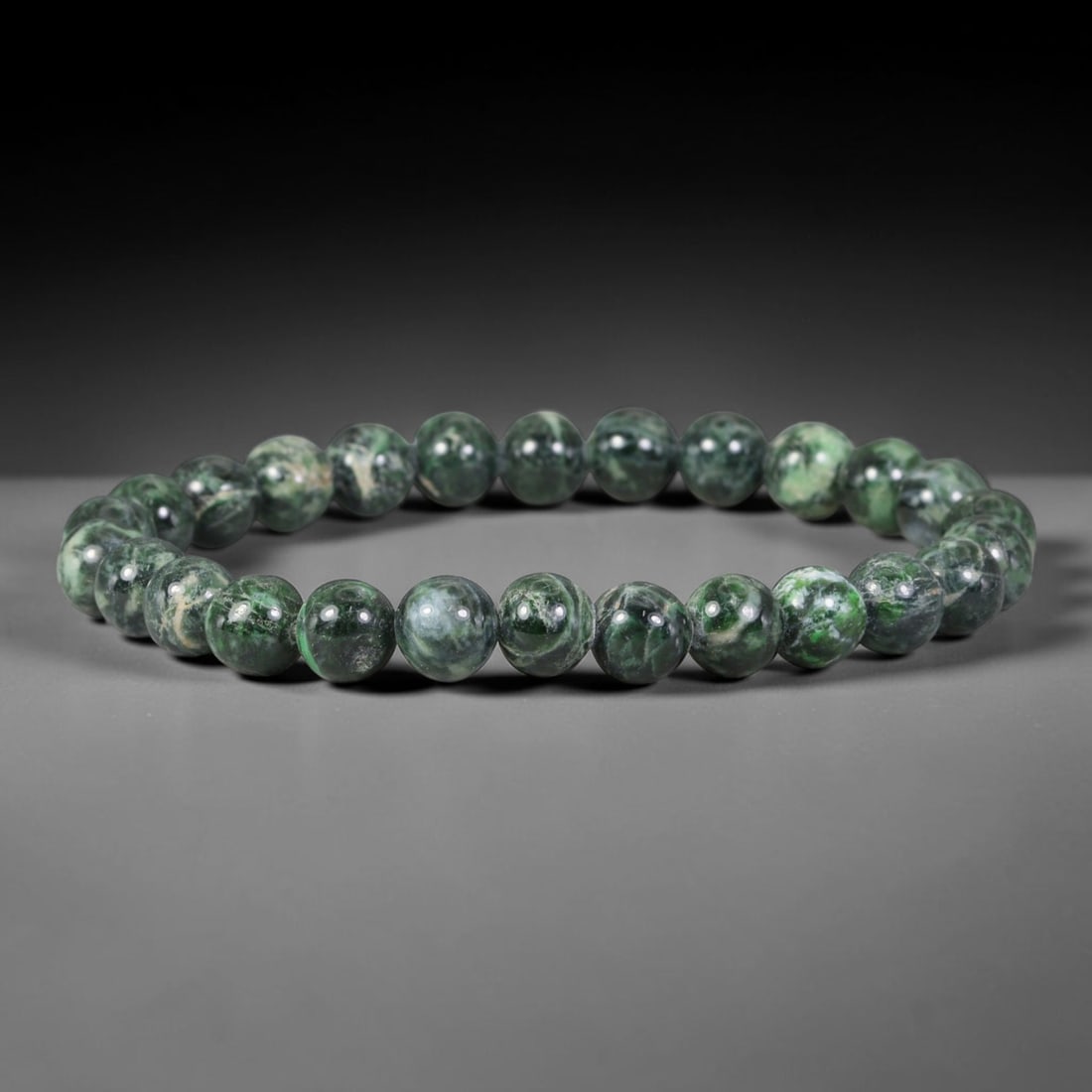 Natural Burmese Type A Deep Green Swirled Mottled Jadeite Jade Bead Bracelet, 42TP: Strung from natural Type A Burmese jadeite, this slender spherical bead bracelet features rich deep forest green interwoven with pale celadon and off-white swirling mottled veining. Each bead is smoot