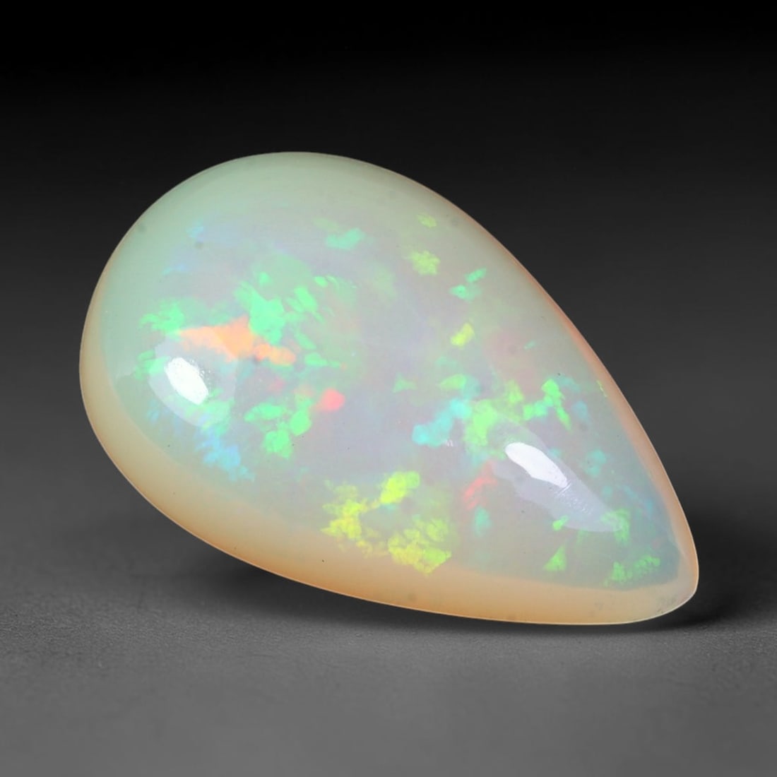 7.94ct Natural Ethiopian Welo Solid Opal Pear Cabochon Loose Gemstone, 9TG: Solid opal cabochon mined from Ethiopia's Welo opal deposits, shaped to a smooth pear teardrop dome with a high-gloss polished finish. The pale milky translucent base holds scattered pinpoint and patc