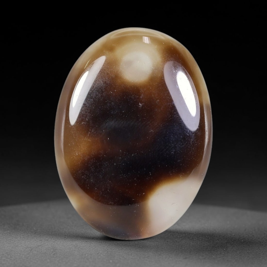 79.25ct Natural Banded Onyx Oval Polished Cabochon, 45TH: This polished specimen is natural banded onyx, shaped as a smooth oval cabochon. The stone features flowing bands of warm tan, deep brown and milky white within a translucent matrix. The surface is fu