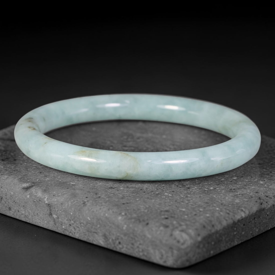 Natural Burmese Type A Pale Celadon Cloud Jadeite Jade Bangle Bracelet, 73TD: Formed from natural Type A Burmese jadeite, this slender rounded bangle features a soft pale celadon base with faint cloudy mottling and subtle light tan mineral flecks dispersed within the stone matr