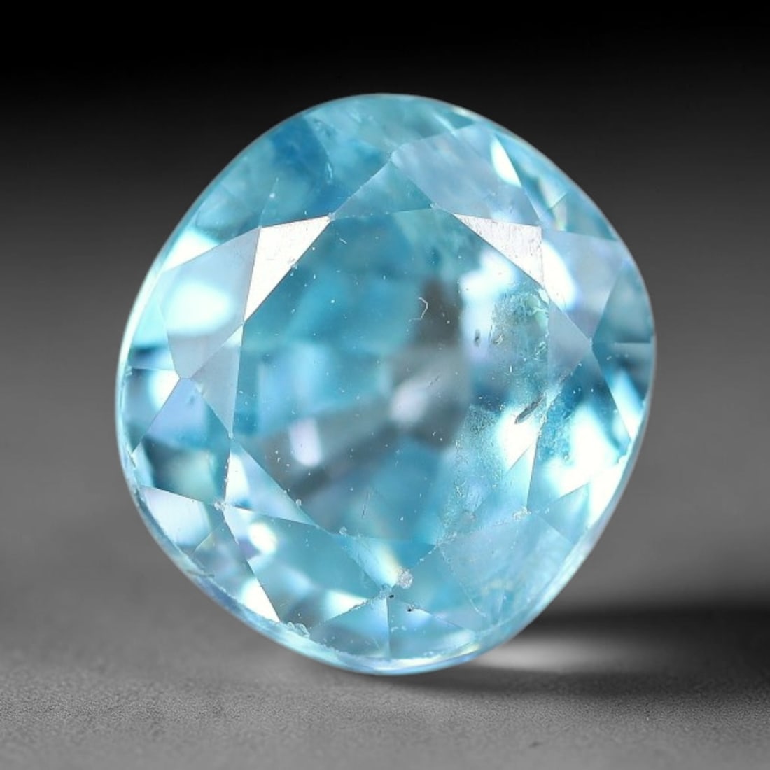 3.74ct Natural Sky Blue Zircon Oval Cut Loose Gemstone, 15TM: This faceted specimen is natural zircon, fashioned in an oval brilliant cut. The stone displays a translucent sky blue hue, with fine internal inclusions visible within the crystal structure. Faceting